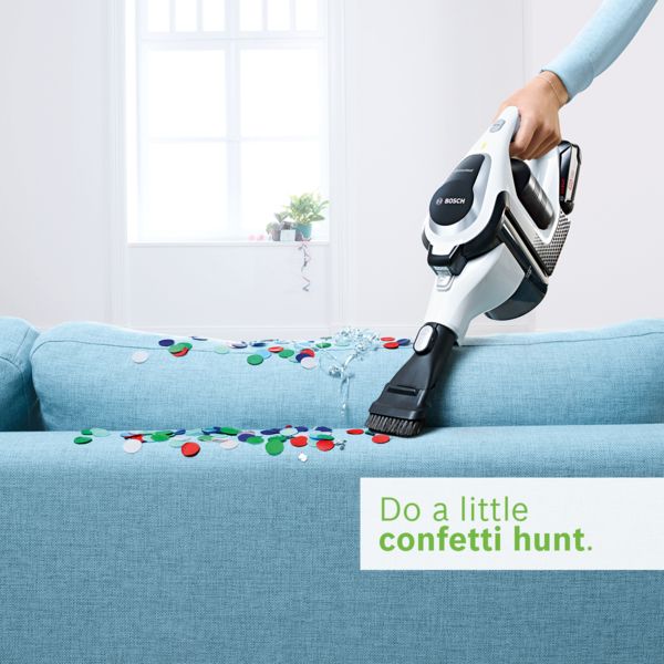 Cordles handheld vacuum cleaner cleaning confetti of a sofa