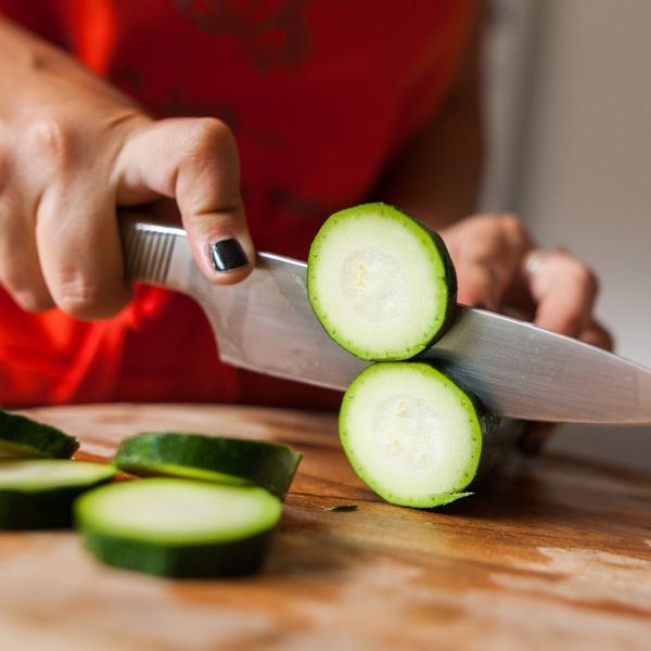 Woman cutting zucchini on cutting board