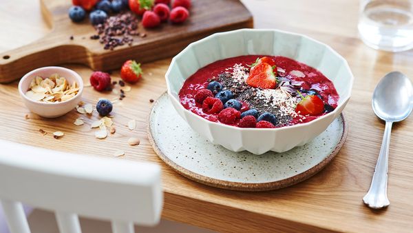 berry smoothie bowl with seeds and nuts on a table