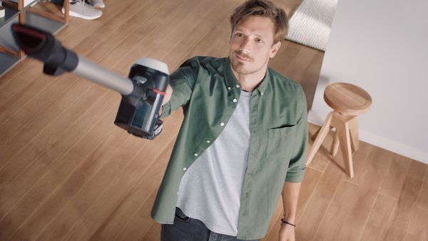 Man vacuum cleaning ceiling with cordless vacuum cleaner