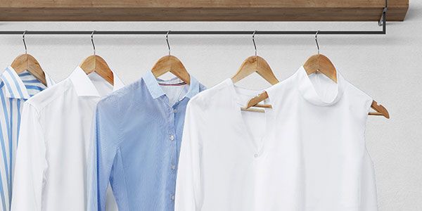 Стойка за дрехи с добре изгладени блузи и ризи