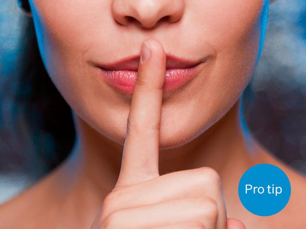 Eine Frau hält sich den ausgestreckten Zeigefinger an die Lippen als Zeichen für "leise".