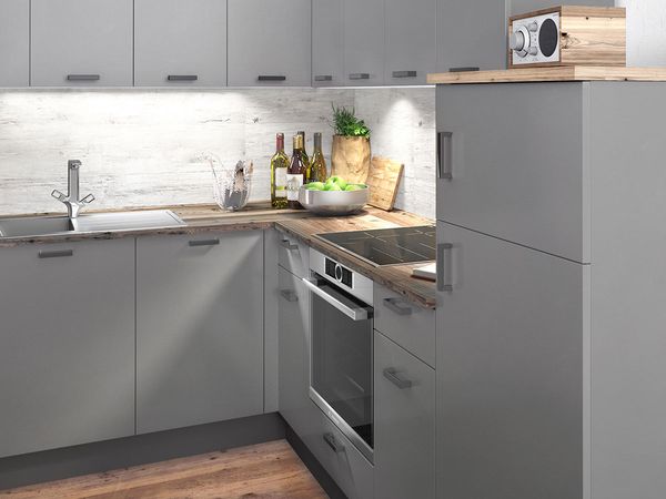 Maža moderni pilkos spalvos virtuvė su mažu įmontuotu šaldytuvu ir dubeniu obuolių ant medinio stalviršio
