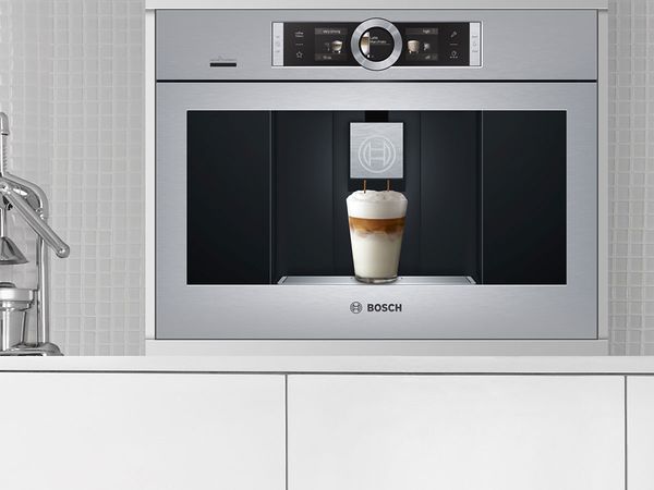 Flush-fitting built-coffee machine in stainless steel with a freshly brewed cappuccino