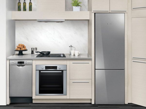 Stainless steel appliance set including an integrated hood in a compact beige kitchen