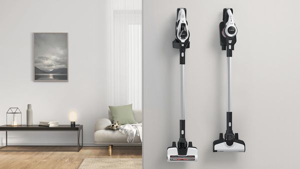 Two cordless vacuums hang on the wall in their charging stations.