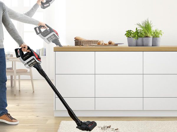A cordless vacuum cleaner is shown in three different positions cleaning from floor to ceiling.