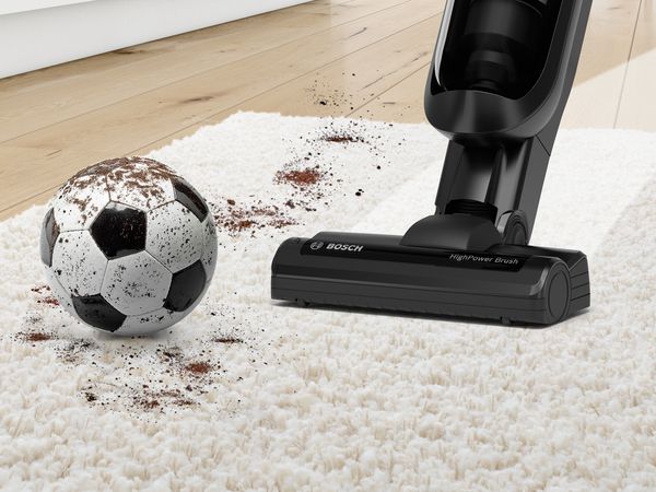 Un aspirator Bosch ProPower curăță murdăria. Pe podea se află o minge de fotbal și pantofi de fotbal.
