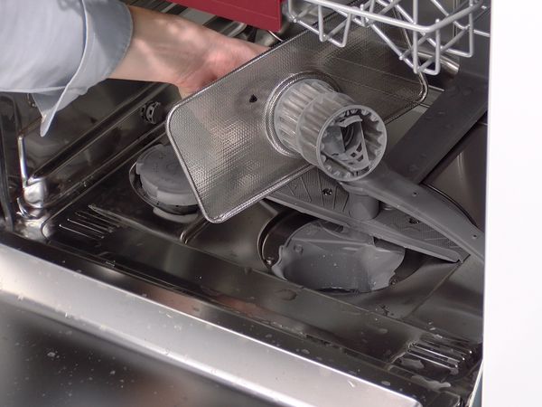 En person holder en filterenhet til en Bosch oppvaskmaskin