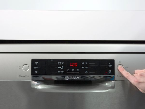 Person pushing the start button on a Bosch dishwasher