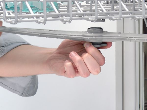 Person detaching a spray arm from a Bosch dishwasher