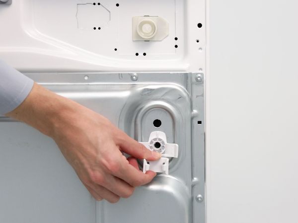 Person removing all sleeves of the transit bolts of a washing machine