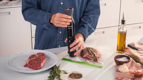 The air inside a vacuum pack with marinated meat is removed with a Bosch hand blender.