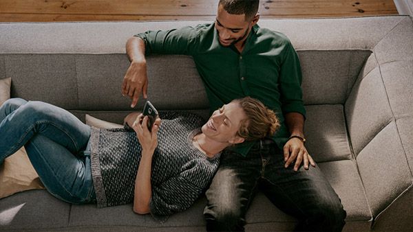 Par på en sofa, der styrer deres hjem med en app på smartphonen