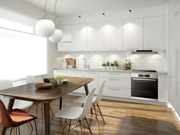 Bright one-wall kitchen with a hood and stove, and a counter lined with fresh herbs and cutting boards