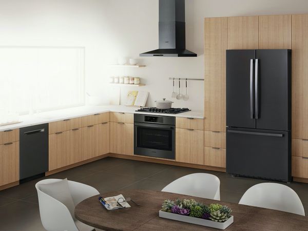 Black Bosch appliances contrast with a spacious L-shaped kitchen in light wood and white and grey marbled counters