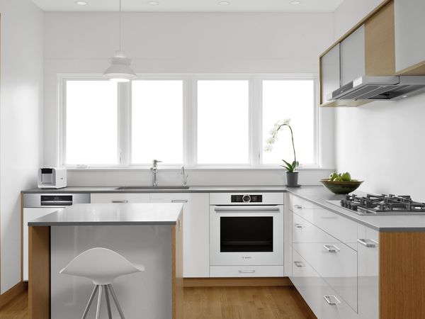 Charming and simple white kitchen with a hint of gloss and white Bosch appliances, including a white oven and gas hob