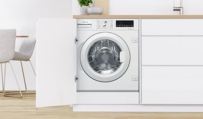 Máquina de lavar roupa sob a bancada da Bosch numa lavandaria branca e moderna.