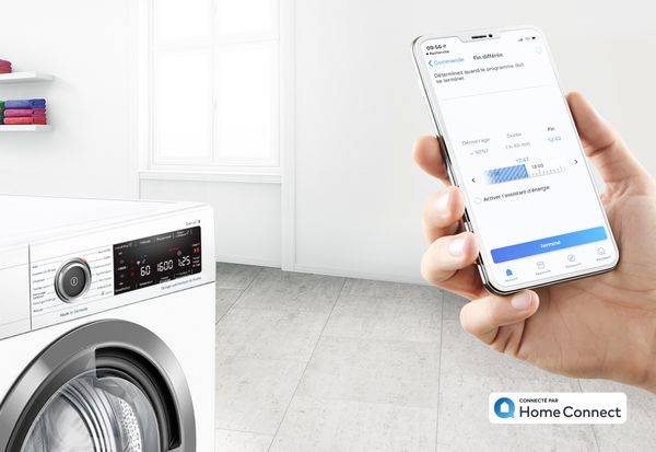 Smartphone avec l'application Home Connect ouverte devant un lave-linge Bosch.