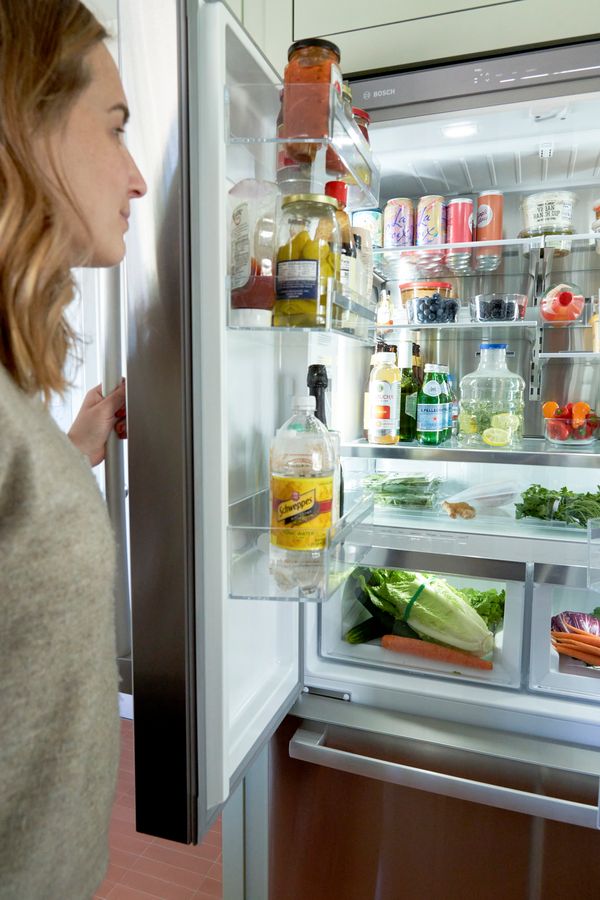 Woman opening left door of Bosch refrigerator