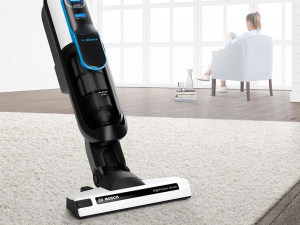  Bosch Athlet ProSilence cordless vacuum cleaning rug while woman reads in background