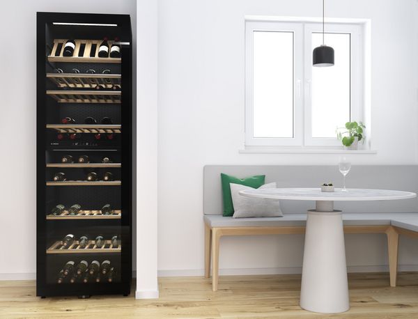 Grande cave à vin pose libre contenant plusieurs bouteilles de vin posées sur des étagères en bois, dans une niche de cuisine moderne 