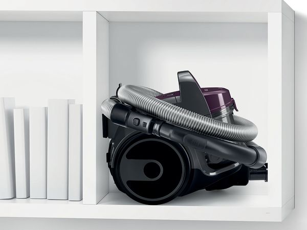 Super compact bagless Bosch vacuum tucked into the end compartment of a lowboard 