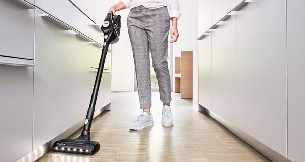 Person vacuuming hardwood kitchen floor with Unlimited cordless stick vacuum cleaner