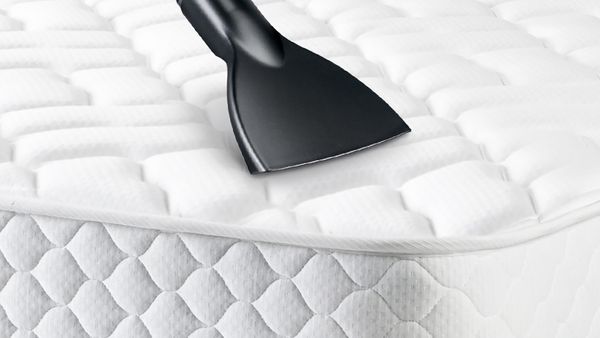 Spezielles Staubsaugerzubehör für Matratzen wird zum Reinigen eines Bettes benutzt.