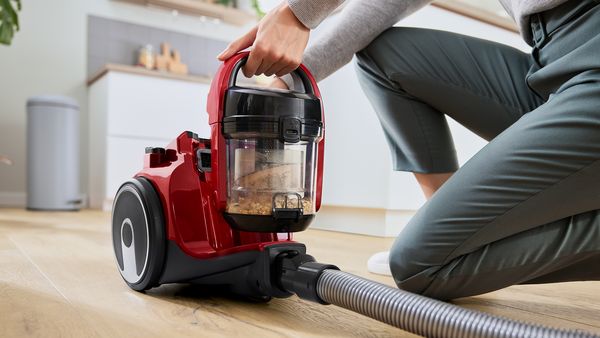 Person using different attachments to vacuum on the floor, sideboard and wall 