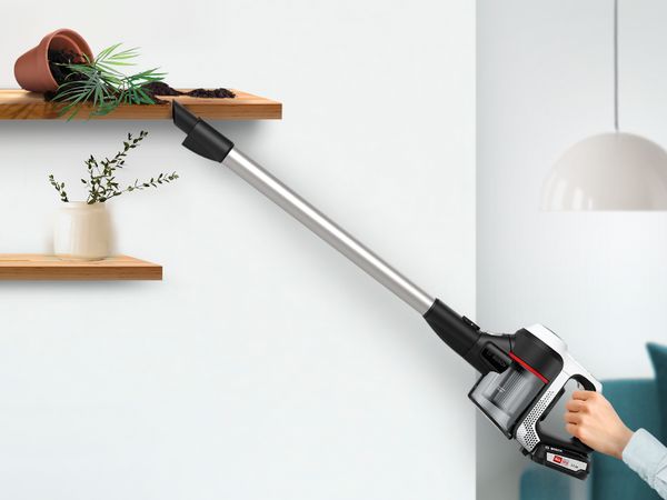 Unlimited Series 6 used as handheld with attachment vacuuming spilled dirt from high shelf