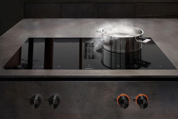 Індукційна варильна панель Gaggenau серії 400 з функцією flex і витяжка, що вбудовується в стільницю, на сучасній кухні.