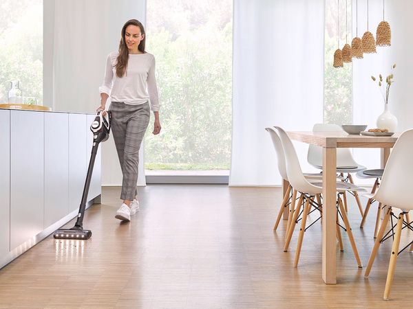 A woman vacuuming a wooden floor with an Unlimited vacuum cleaner.
