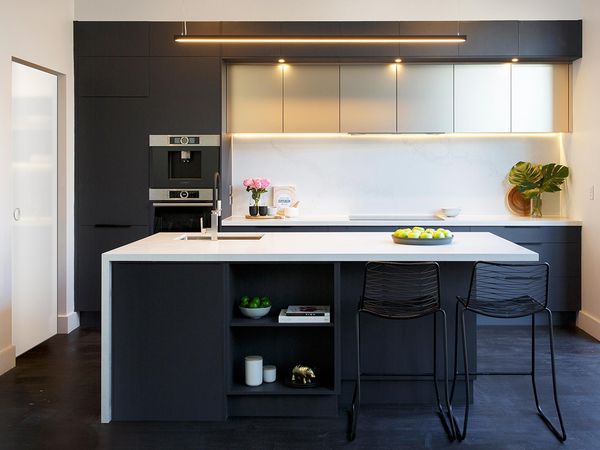 Small, modern black and white kitchen with built-in cooking appliances and white crockery on open shelves