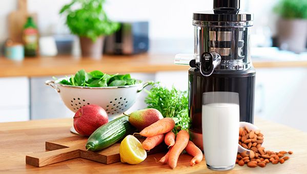 Frau macht in moderner K&uuml;che gr&uuml;nen Smoothie mit Mixer. 