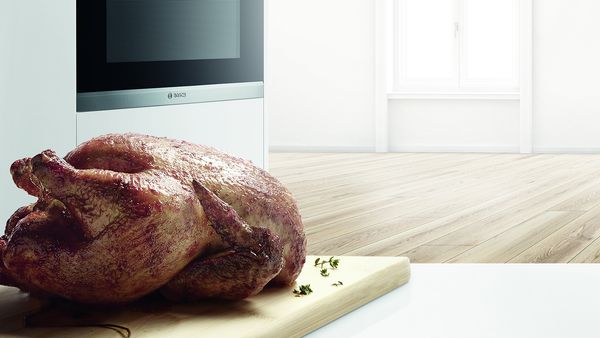 Roast chicken on a chopping board in a kitchen