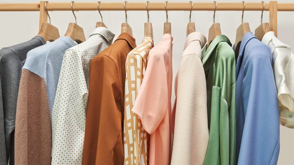 Collezione di camicie colorate appese su un appendiabiti, mostrando una variet&agrave; di stili e tonalit&agrave;.