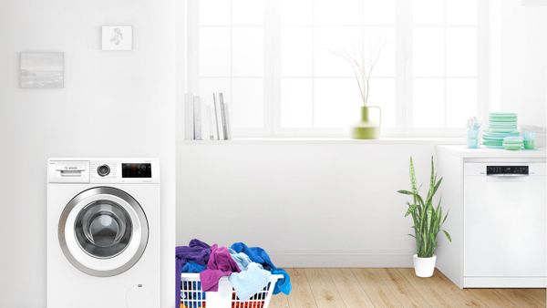 Tidy laundry nook with colourful towels in a basket next to a Bosch washing machine 