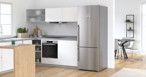 Просторна кухня с вграден сребрист хладилник Bosch. Модерна трапезария на заден план.