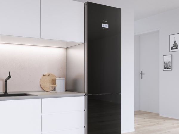 Висококачествен и надежден черен хладилник с фризер Bosch в модерна бяла кухня.