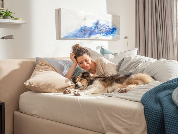 Donna a letto con il cane sdraiato accanto