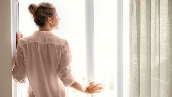 Donna che respira aria fresca accanto a una finestra