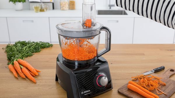 A food processor being used to grate vegetable.
