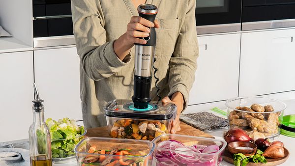 A Bosch hand blender being used to vacuum seal compatible containers.