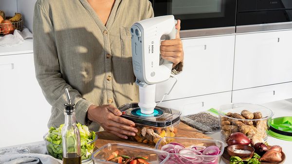 A person vacuum sealing a container with a Bosch hand mixer.