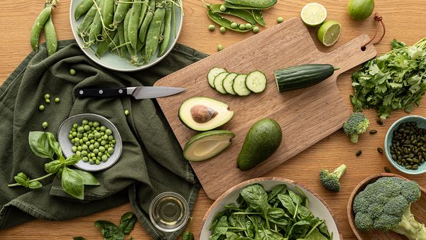 Ingredienti per un'insalata con verdure verdi disposti sul tavolo.