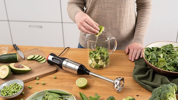 Preparazione della salsa per l'insalata verde: frullare succo di lime e avocado pelato con un frullatore a immersione.