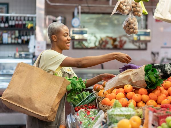 Giovane donna che al mercato sceglie frutta e verdura di stagione