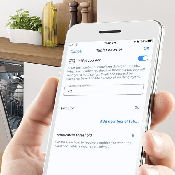 Eine Person ruft über die mobile Home Connect App Informationen zum Vorrat an Geschirrspültabs ab.
