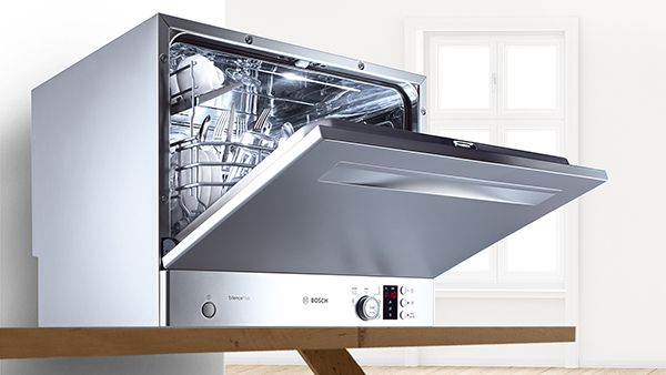 Bosch bänkdiskmaskin i rostfritt stål med luckan på glänt på en köksbänk.